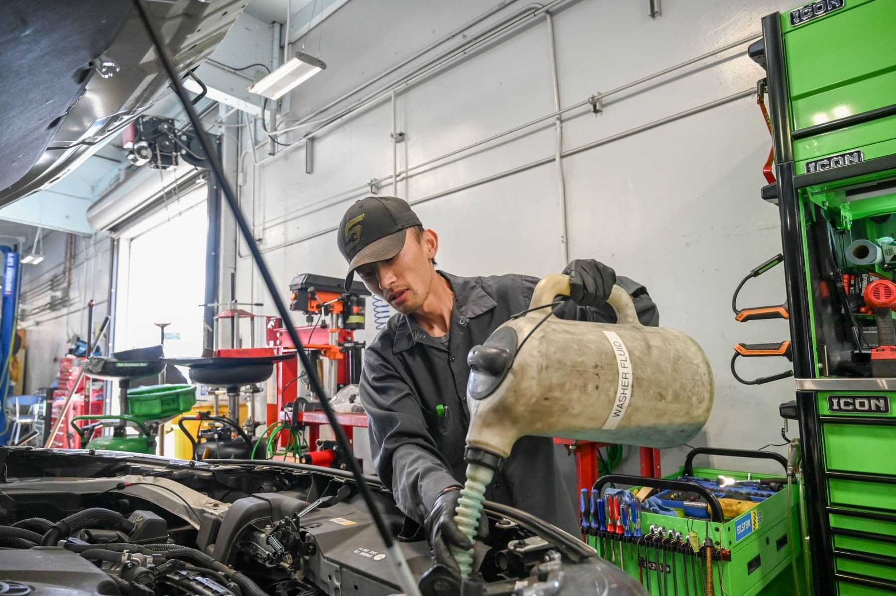 Topping up fluid under the hood at Earthling Automotive